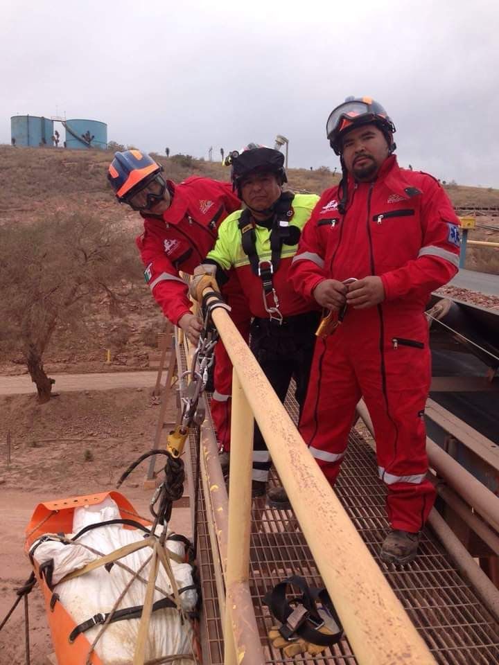 Tres hombres con monos rojos están de pie sobre una barandilla.