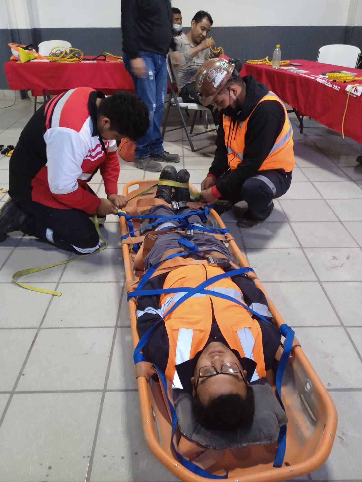 Un hombre en una camilla está siendo medido por dos hombres.