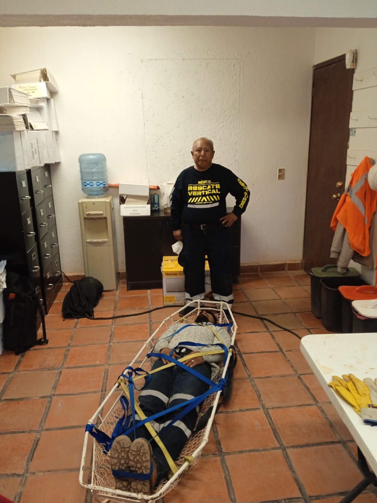 Un hombre está de pie junto a una camilla con una persona dentro.