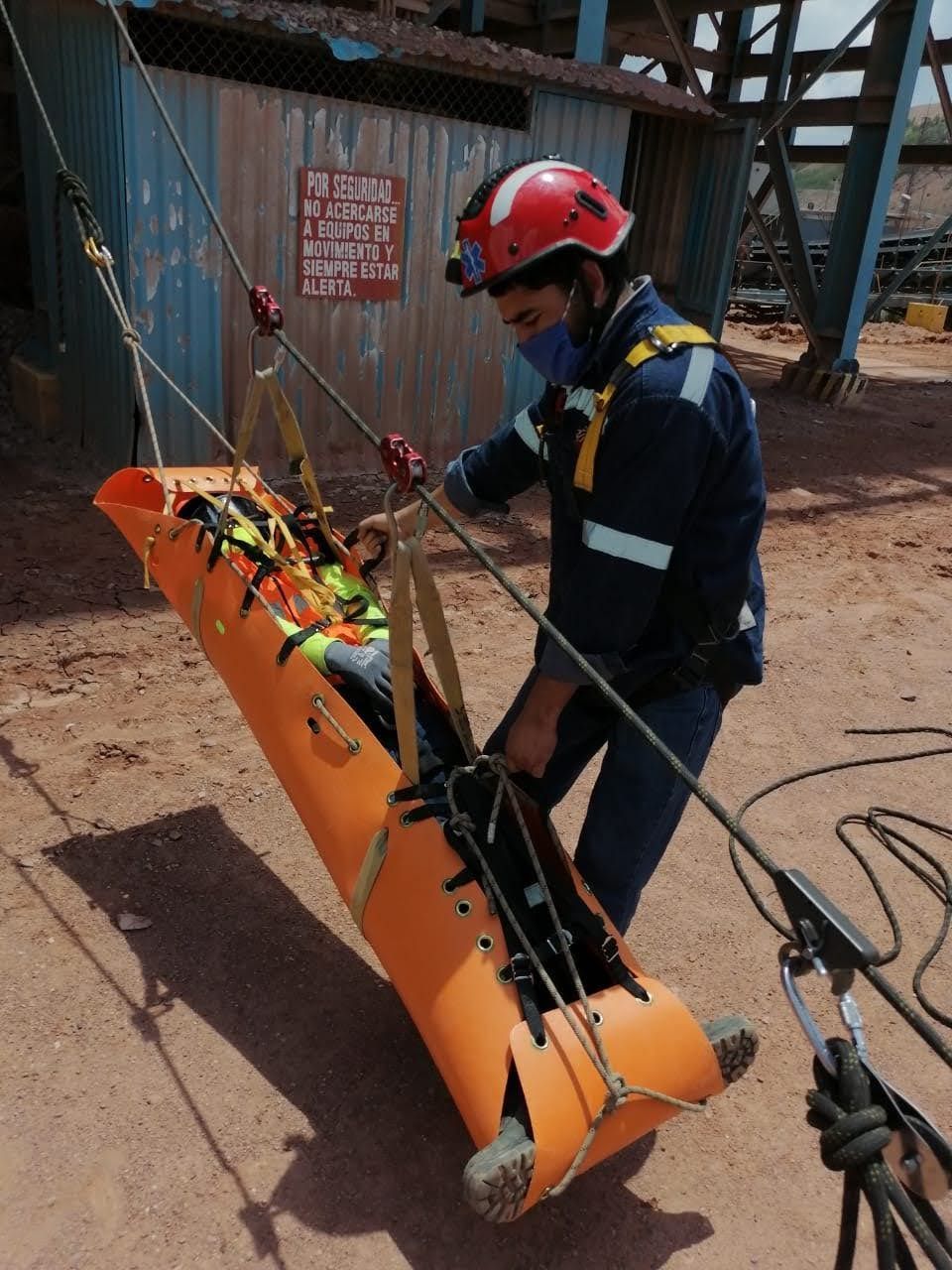 Un hombre que lleva un casco lleva una camilla naranja.