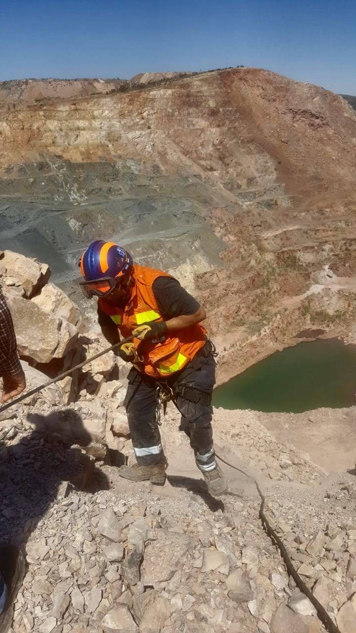 Un hombre con casco está parado en la cima de una colina rocosa.
