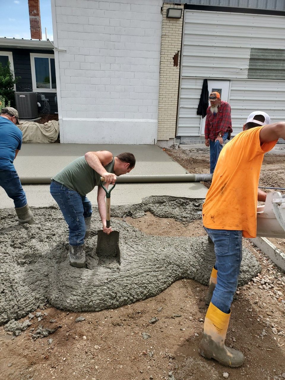 A group of construction workers are pouring concrete on a sidewalk.