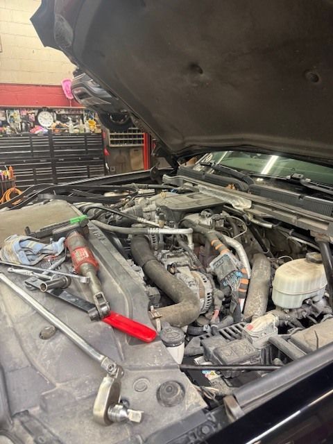 An open hood of a truck engine bay in a garage, featuring tools laid out on the radiator shroud during maintenance. | Orillia Steer And Stop