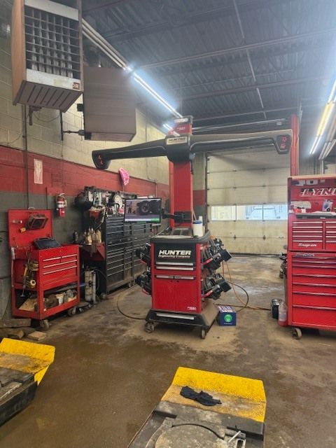 A red Hunter wheel alignment machine stands in a professional auto repair garage with tool chests and equipment nearby. | Orillia Steer And Stop