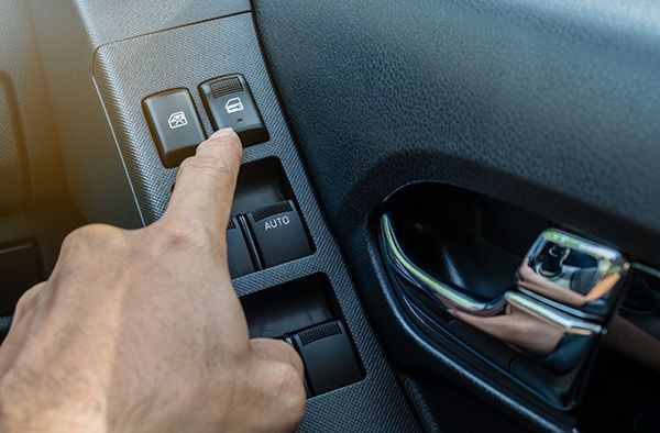 A person is pressing a window switch in a car.  | Carmasters Automotive