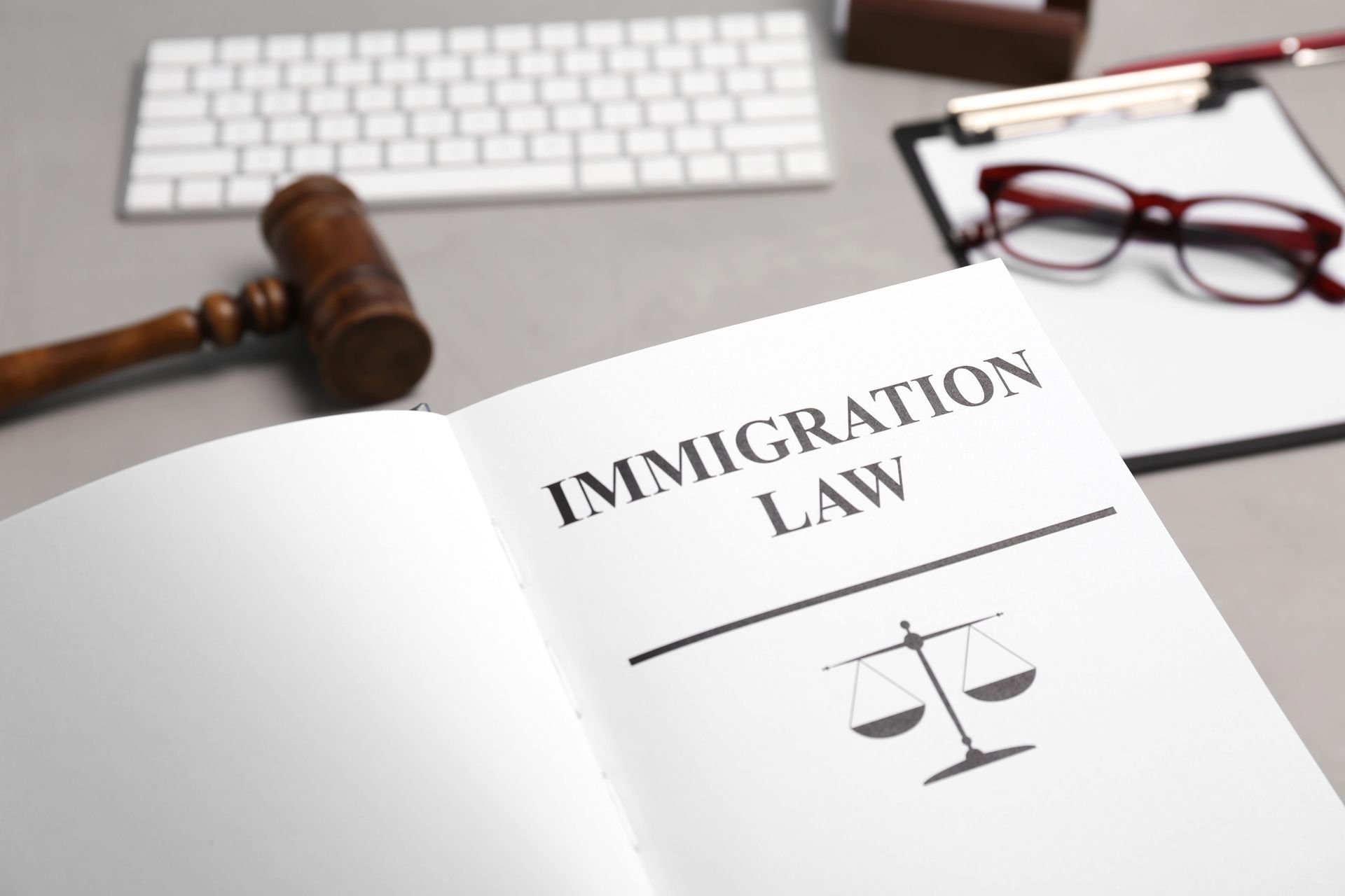Immigration law book on desk with gavel, keyboard, and eyeglasses