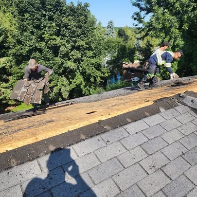 Two men are working on the roof of a house.