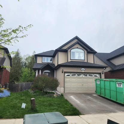 A red car is parked in front of a brick house