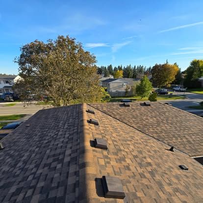 A roof with a tree in the background and a blue sky in the background.