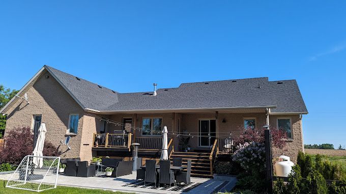 Rear view of a brick house with a deck, patio, and blue sky.