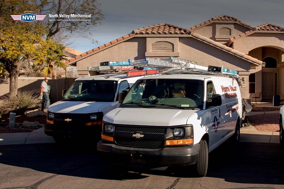 Two white vans are parked in front of a house