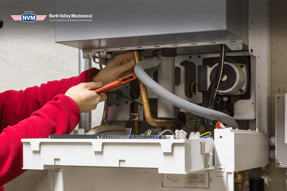 A person is fixing a boiler with a wrench.