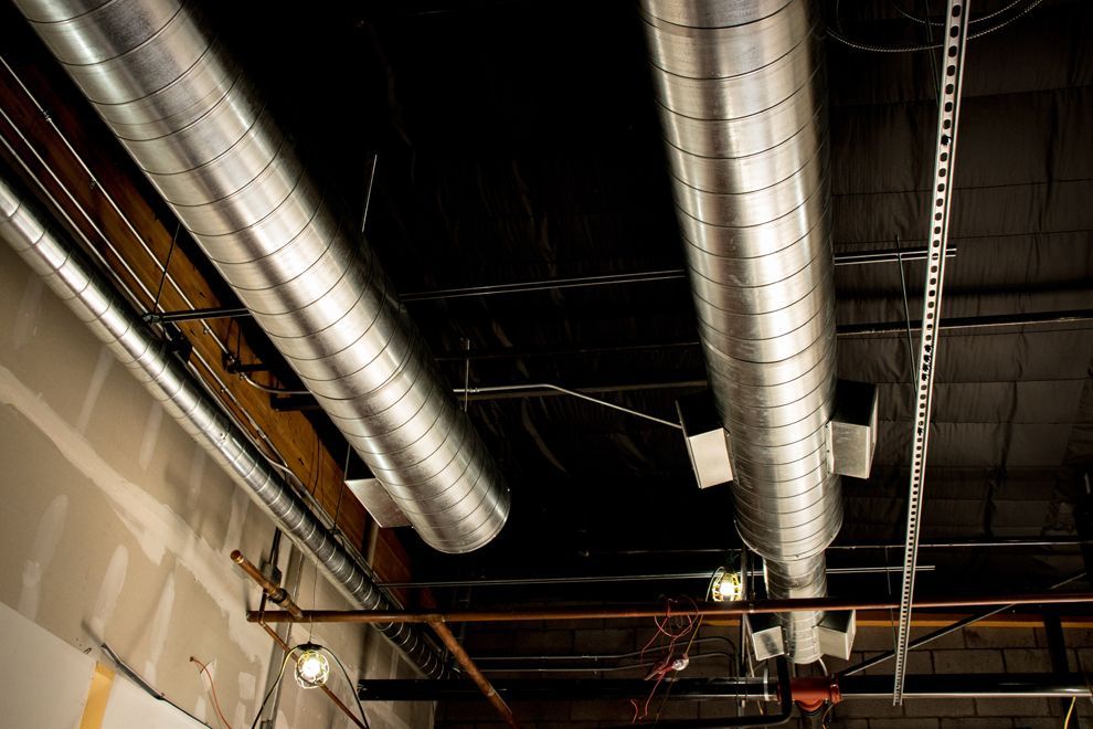 A bunch of metal pipes are hanging from the ceiling of a building.