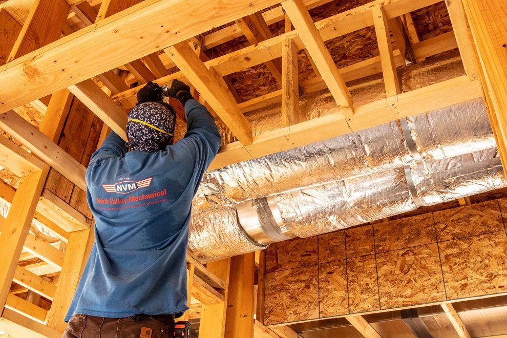 A man is working on a duct in a building under construction.