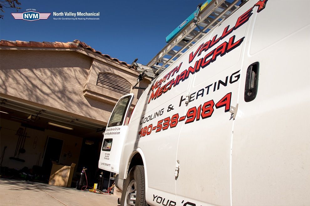 A white van with a ladder on top of it is parked in front of a house.