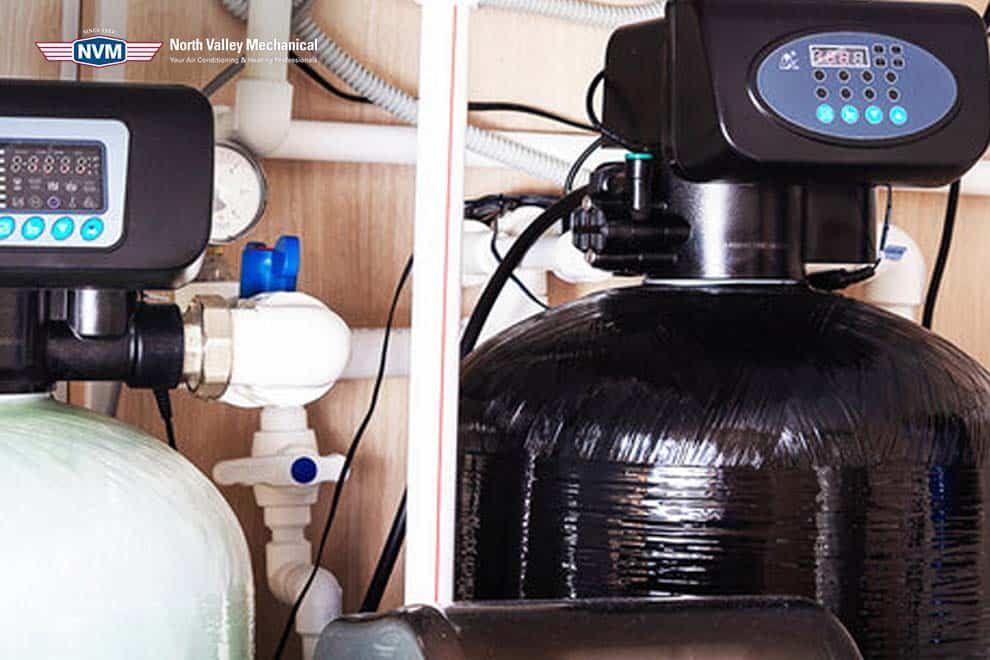A water filter is sitting under a sink in a kitchen.