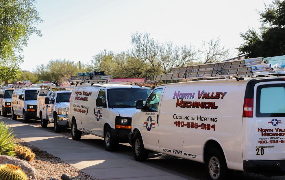 A row of north valley mechanical vans are parked on the side of the road.