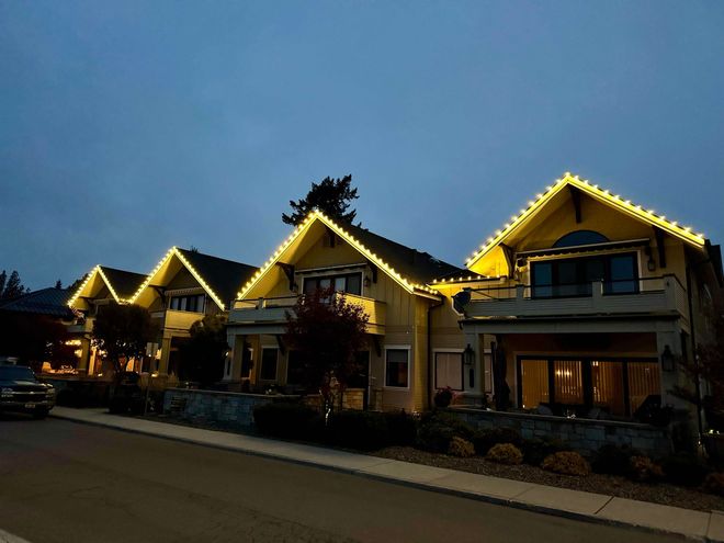 Row of chalet-style houses lit with warm yellow lights at dusk