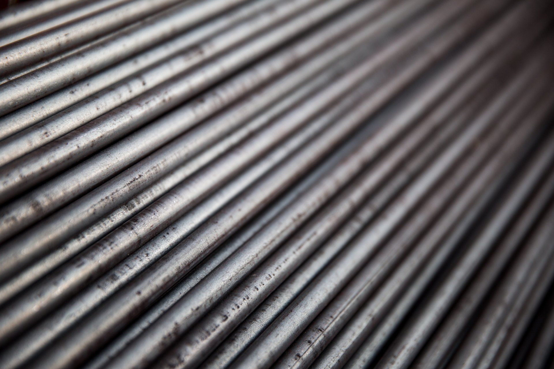 Vista ravvicinata di una pila di barre metalliche parallele. Le barre sono argentate e leggermente lucide.
