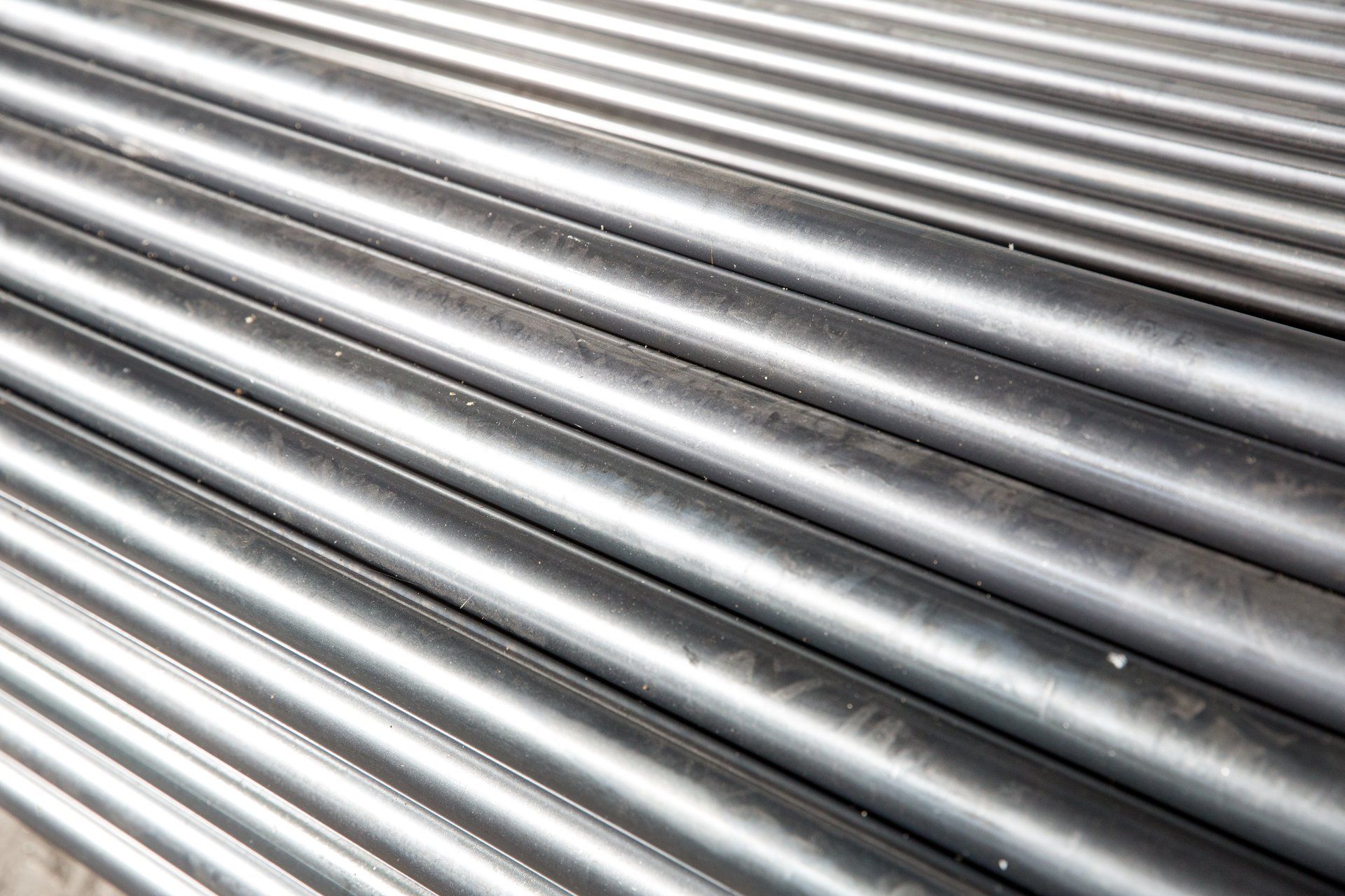 File di tubi metallici, probabilmente in acciaio, in un ambiente industriale.