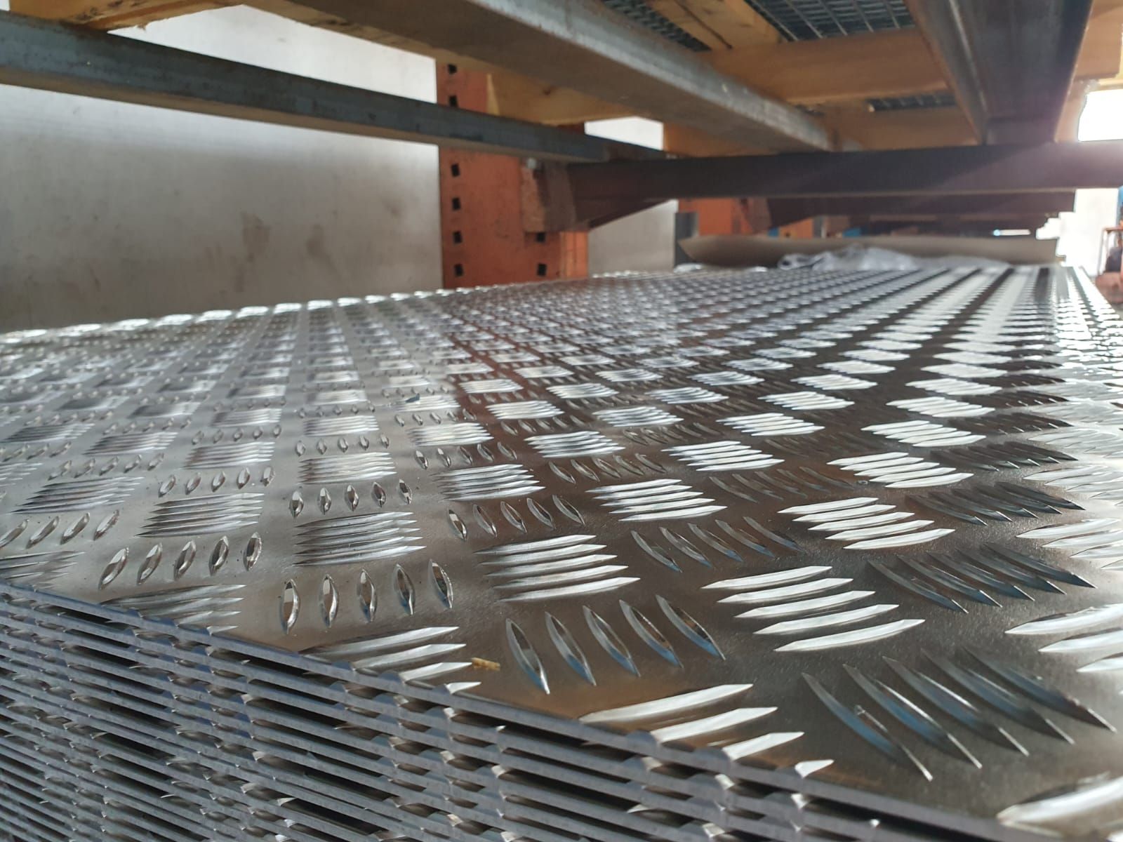 Pila di lamiere diamantate, primo piano, sotto una trave di supporto.