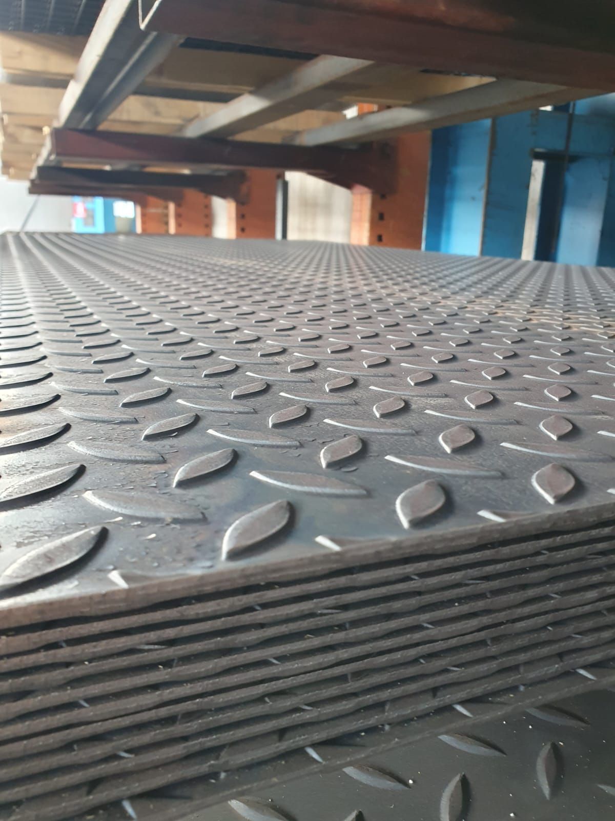 Pila di lamiere diamantate in un ambiente industriale.