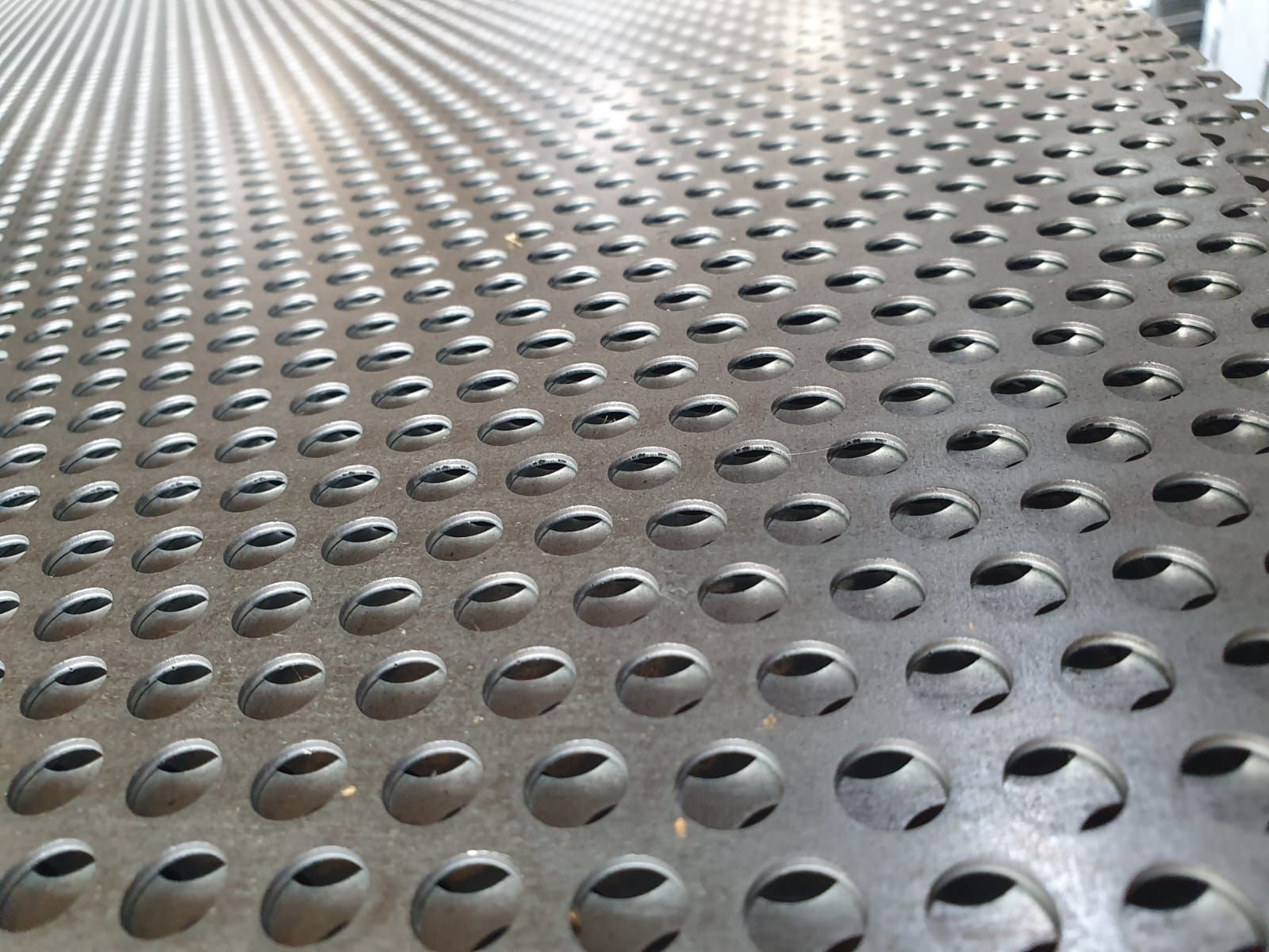 Lamiera metallica perforata con numerosi fori circolari uniformemente distanziati.
