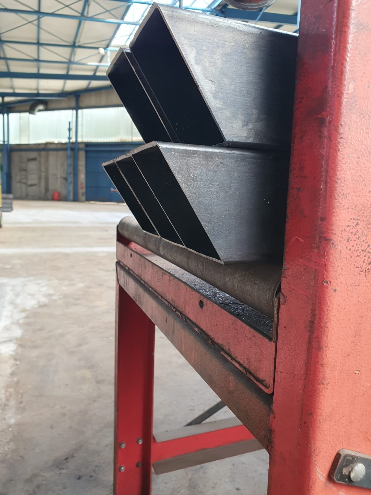 Pezzi di metallo in una macchina di formatura. Macchina rossa, metallo grigio. Ambiente industriale.