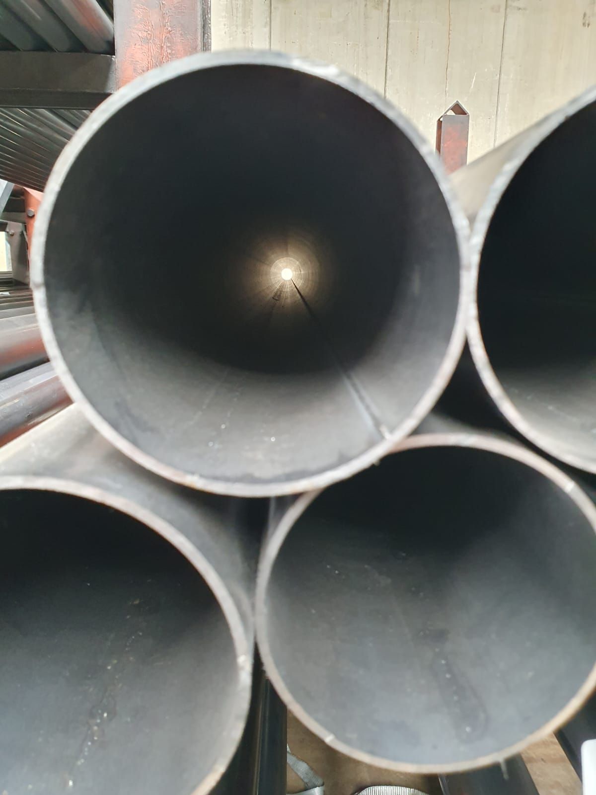 Pila di tubi metallici cilindrici; interni grigi e neri visibili.