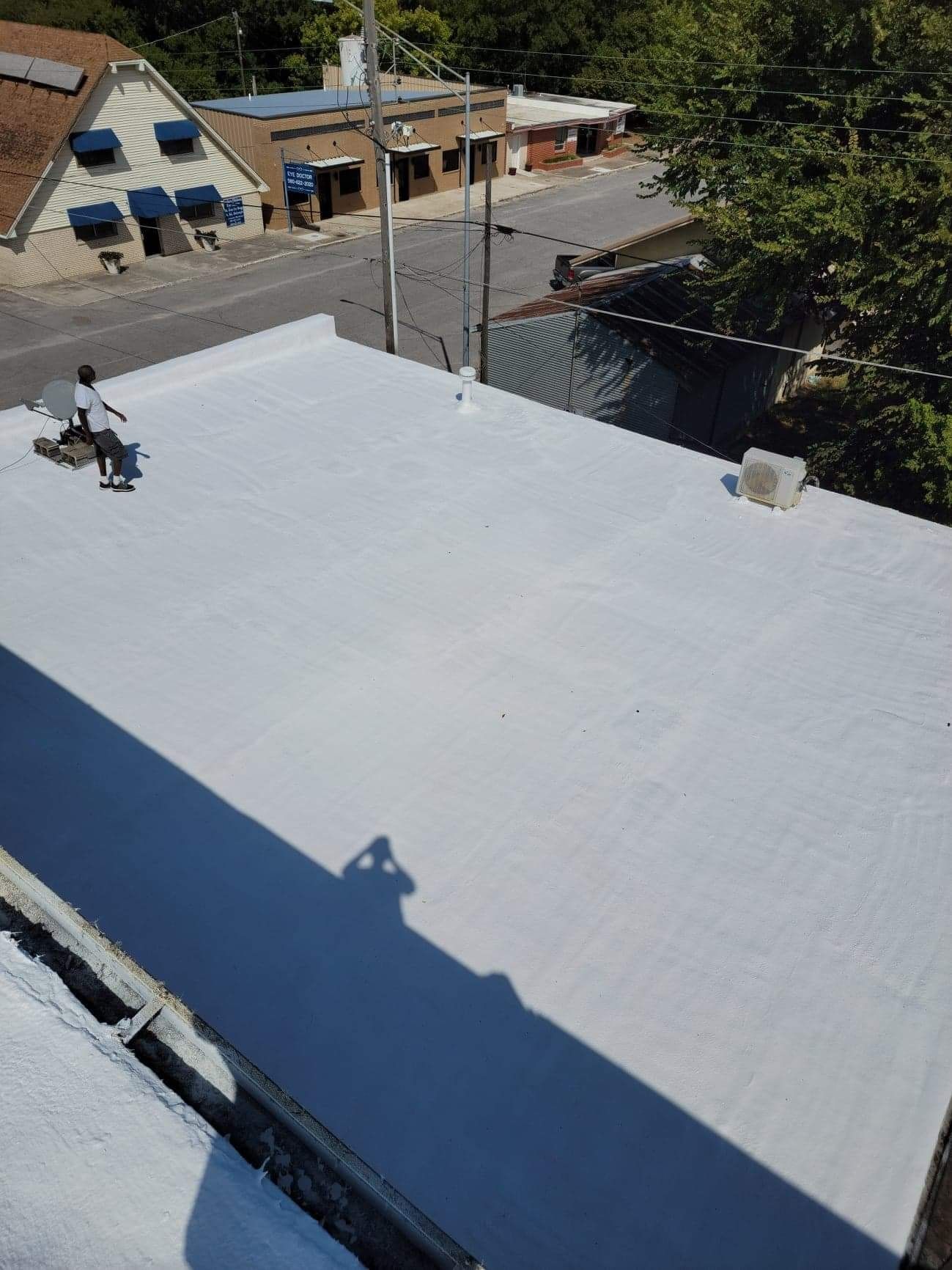 A man is standing on top of a white roof.