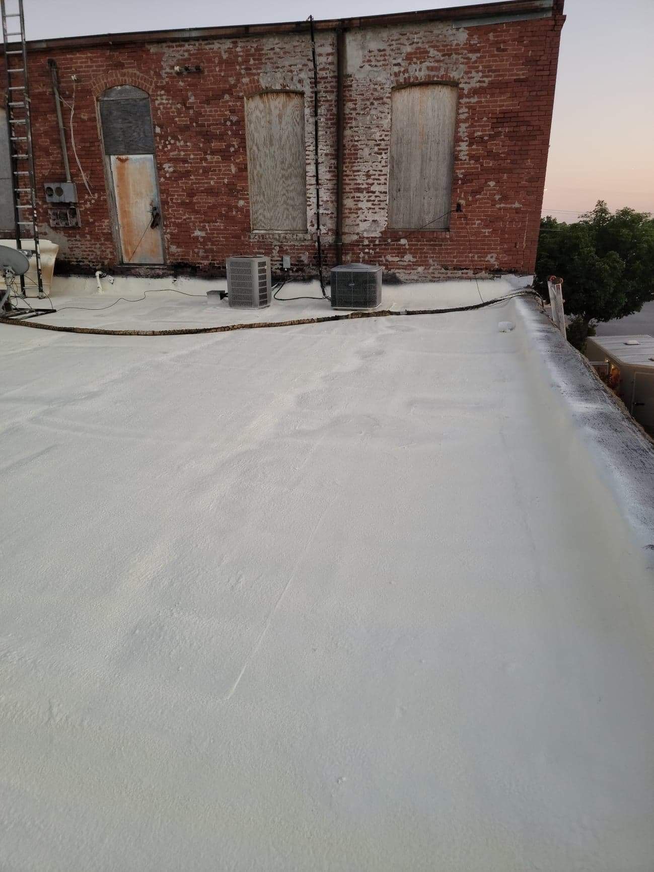 A white roof with a brick building in the background.