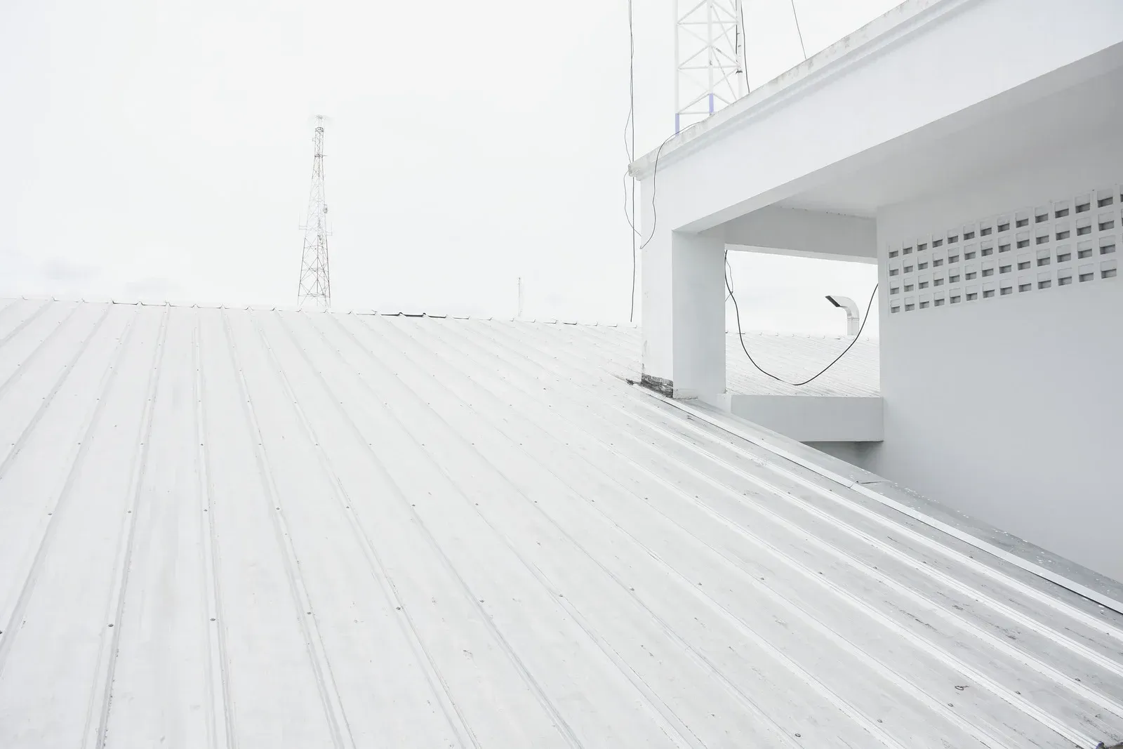 White metal roof with a white building and a tall radio tower.