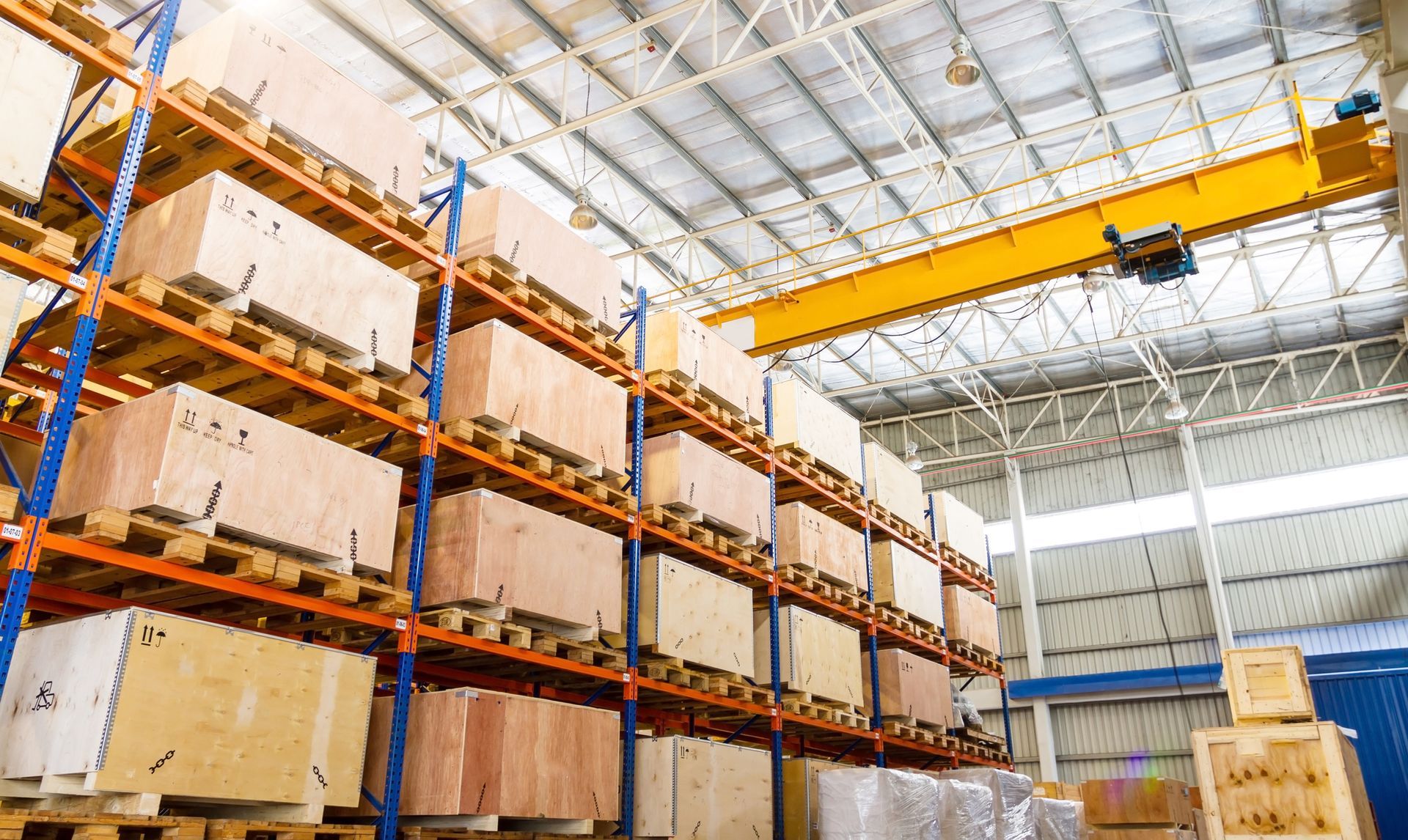 Shelves and racks inside a warehouse interior from below. The shelves are full of wooden crates.