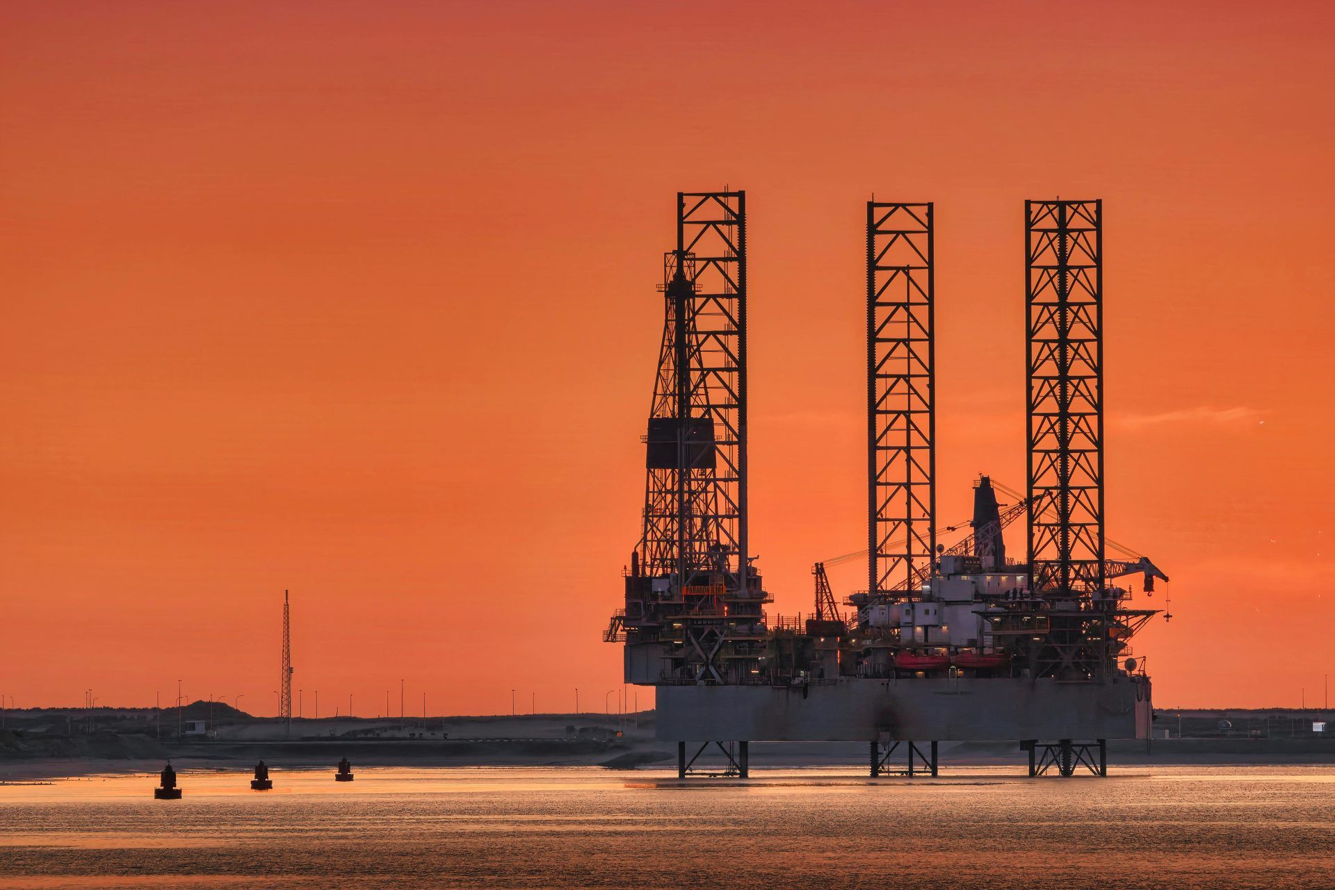 An oil rig in the middle of the ocean at sunset.