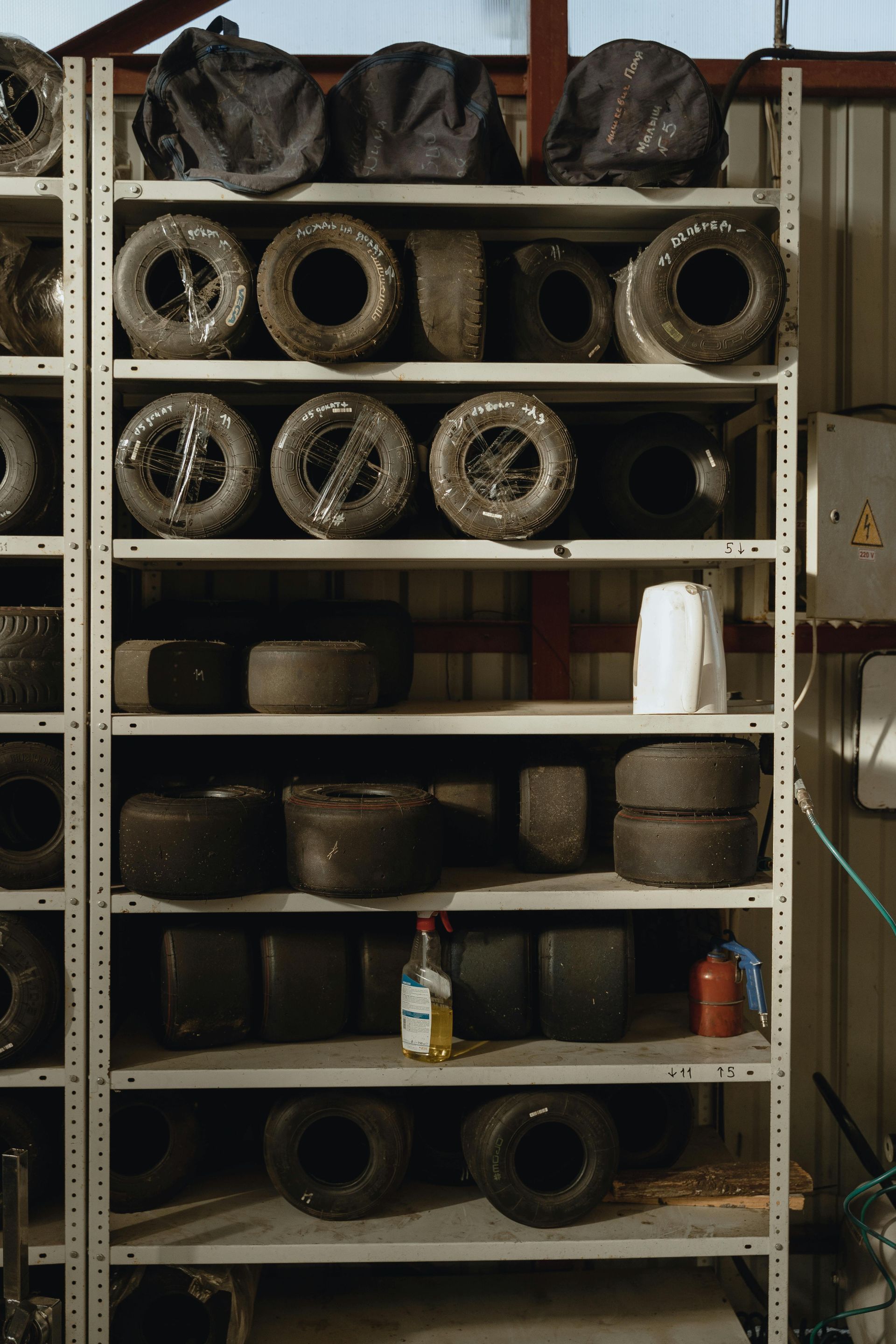 A shelf filled with lots of tires and wheels in a garage.