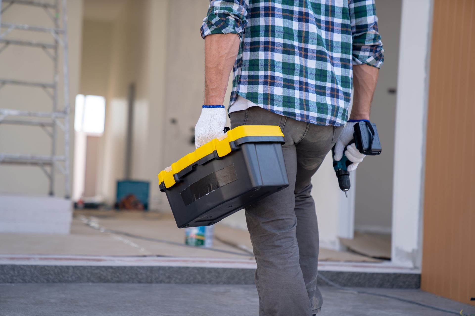A man is carrying a toolbox and a drill.