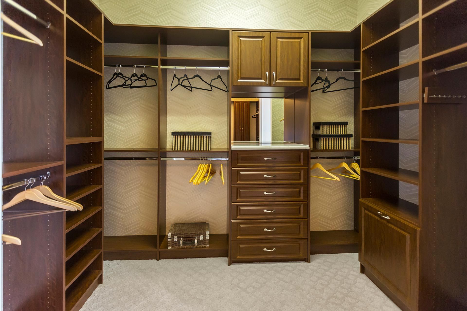 A walk in closet with lots of shelves and drawers