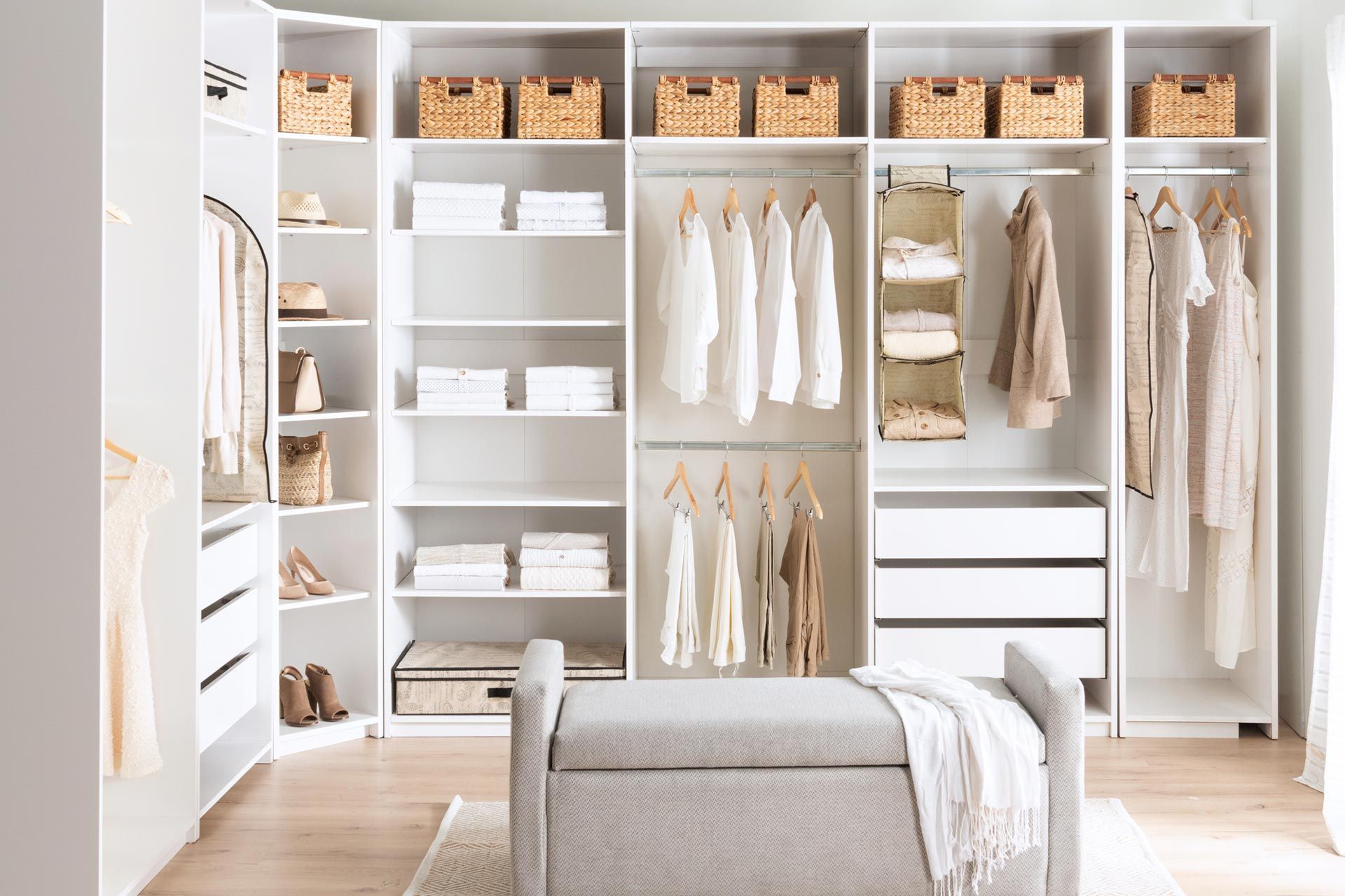 A walk in closet filled with lots of clothes and a bench.