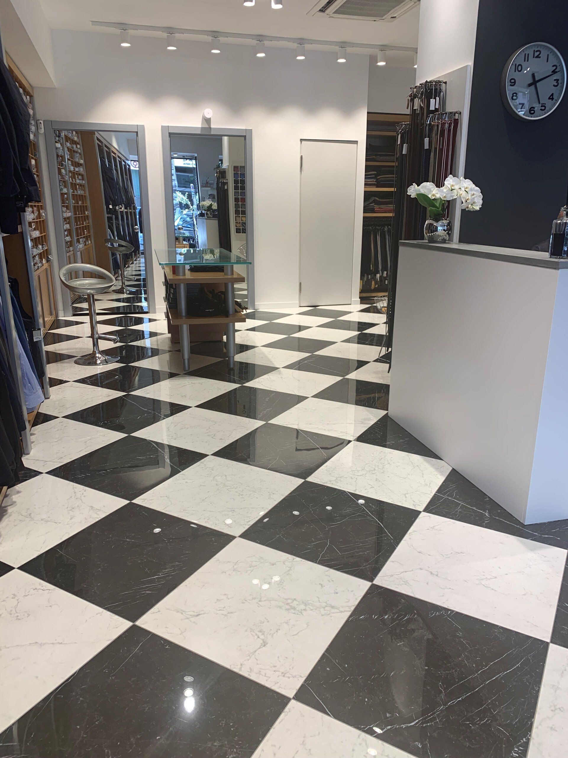 Un pavimento a scacchi in un negozio con un orologio sul muro