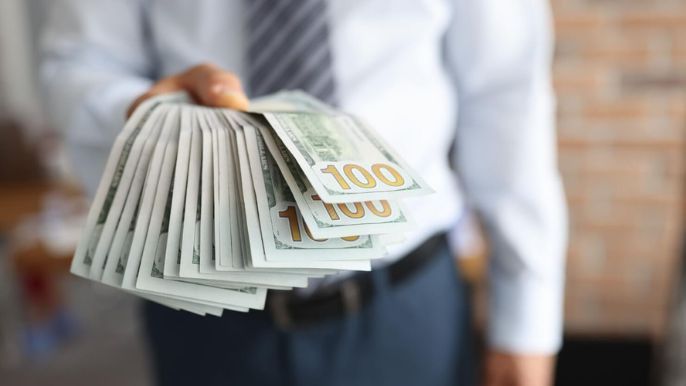 A man is holding a stack of money in his hand.
