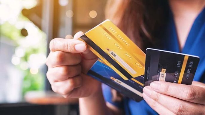 A woman is holding two credit cards in her hands.