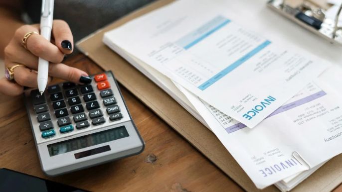 A woman is using a calculator to calculate an invoice.