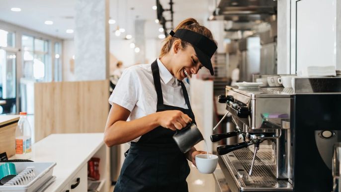 A woman is pouring milk into a cup of coffee.
