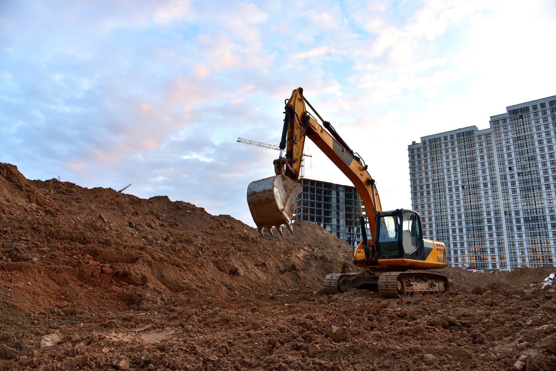 An excavator is digging a hole in the dirt at a construction site.