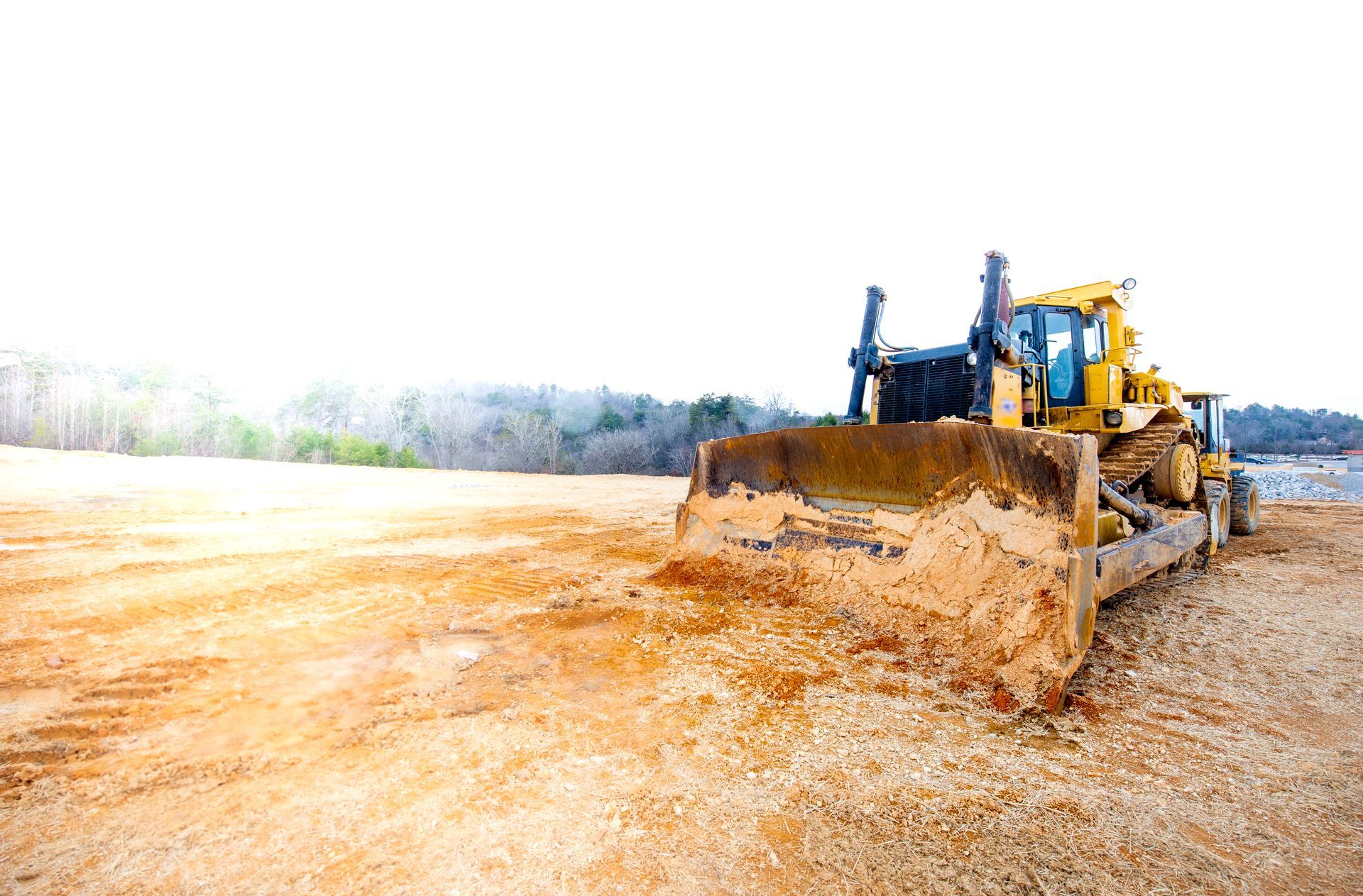 A yellow bulldozer is moving dirt on a construction site.