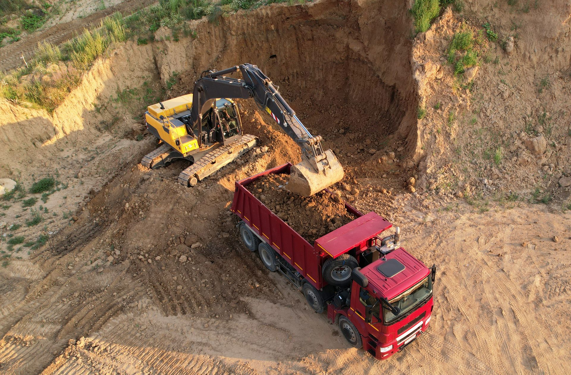 An excavator is loading dirt into a dump truck in a quarry.
