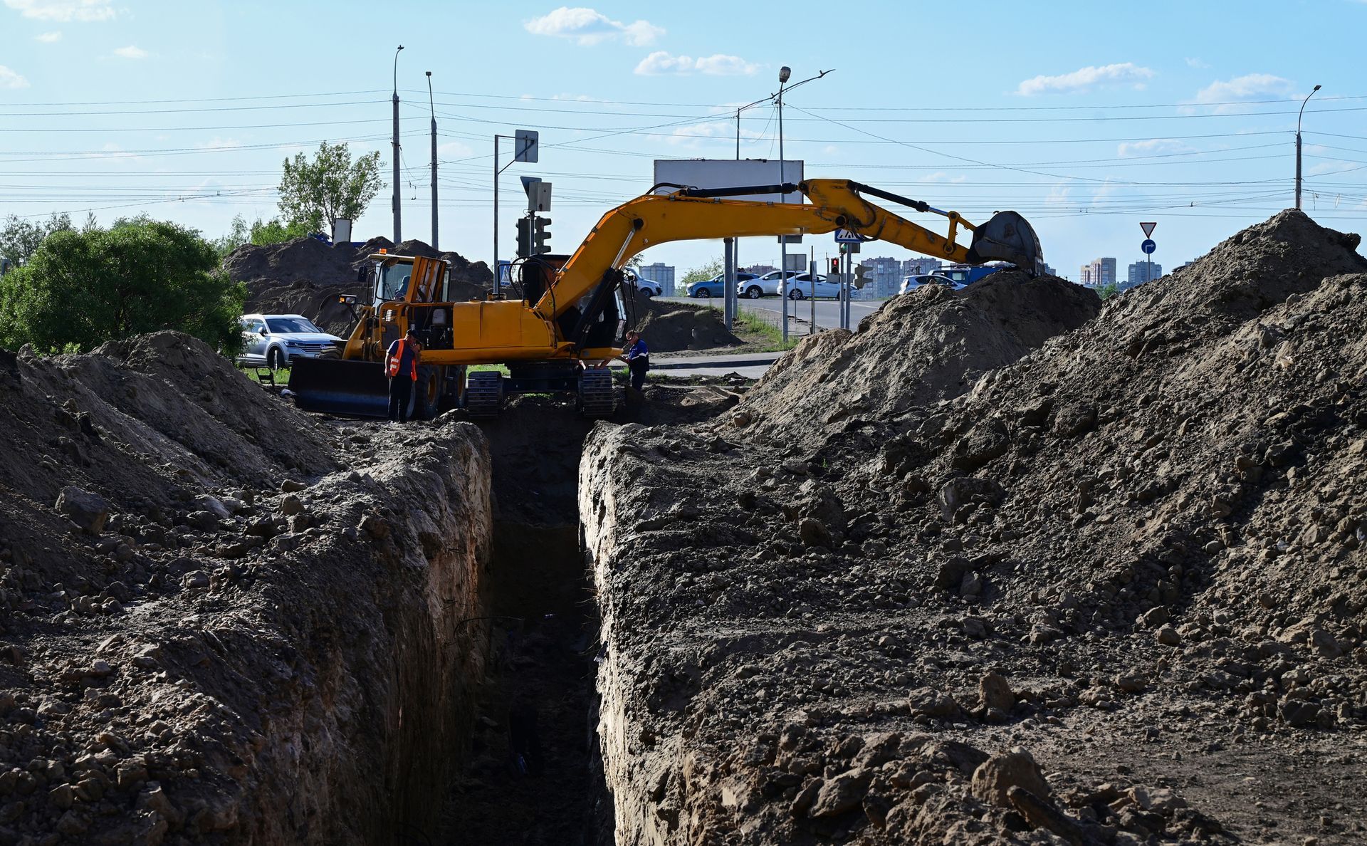 A yellow excavator is digging a trench in the dirt.
