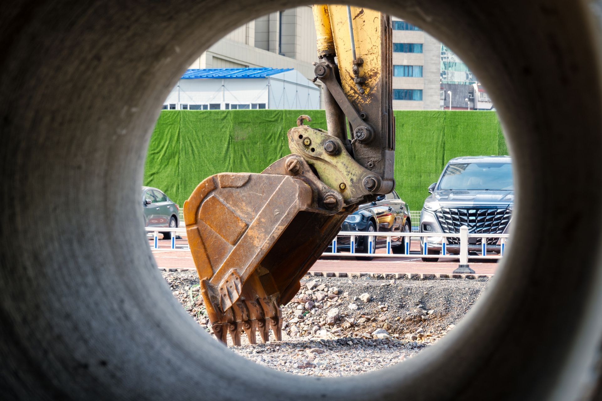 A view of a construction site through a hole in a pipe.