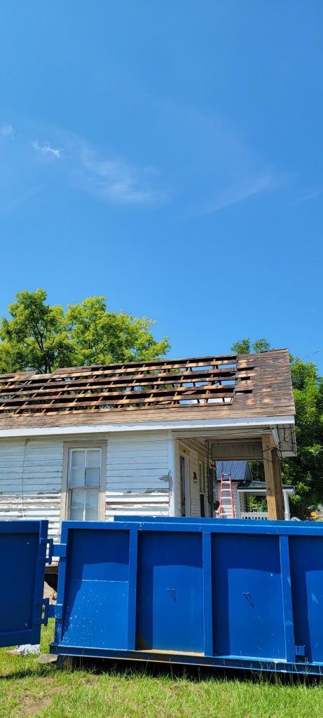 A Blue Dumpster is Sitting in Front of a House That is Being Demolished