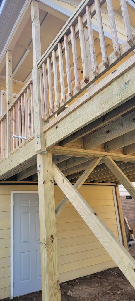 A Wooden Deck is Being Built on Top of a Yellow House